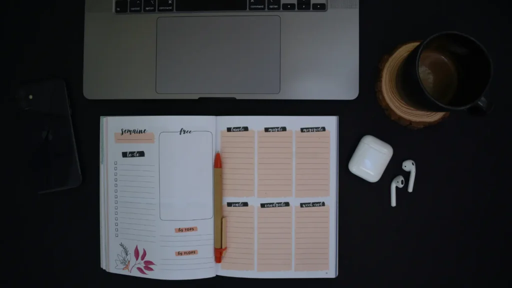Portátil con hoja de cálculo de presupuesto junto a checklist impreso en papel sobre la misma mesa de trabajo, representando las dos herramientas complementarias para organizar una boda sin estrés: el checklist PDF para los plazos y la plantilla Excel para el control financiero