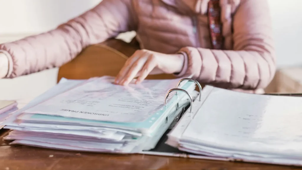Persona revisando varias facturas y documentos de contratos sobre una mesa de trabajo organizada sin texto legible, representando el sistema de control de pagos y plazos necesario para coordinar doce o más proveedores de boda sin perder dinero en duplicidades u olvidos