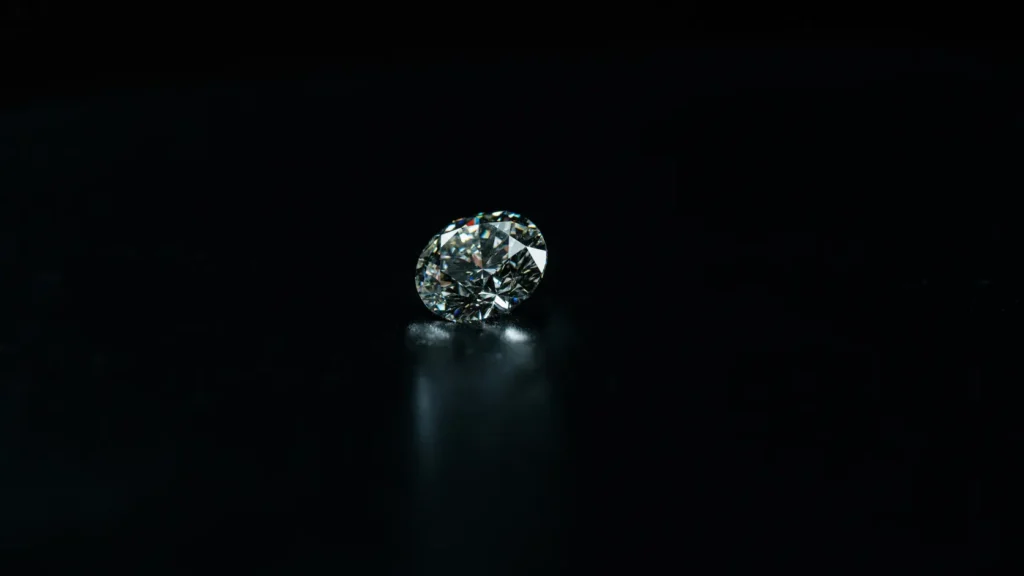 Diamante suelto de corte brillante sobre superficie oscura bajo iluminación de joyería profesional sin texto ni instrumentos visibles, representando la guía práctica de las 4C para elegir un diamante sin pagar de más en 2026