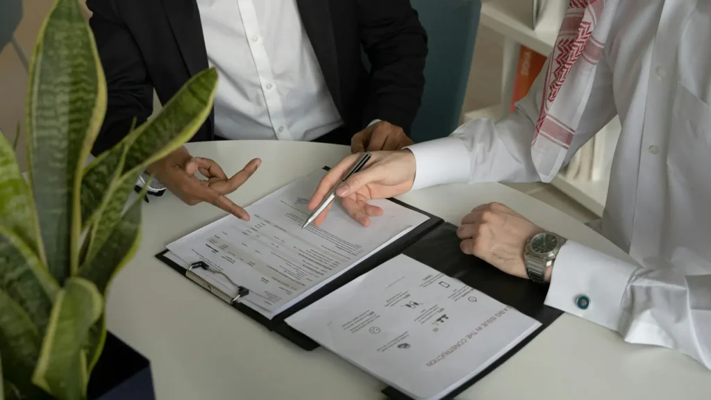Dos personas en reunión de negociación frente a documentos con expresión seria y concentrada sin texto visible, representando cómo negociar con proveedores de boda para incluir cláusulas de cancelación, presupuesto cerrado e IVA incluido antes de pagar la señal