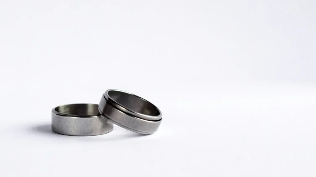 Par de alianzas de boda, una de oro blanco y otra de platino, colocadas sobre fondo oscuro de terciopelo sin texto visible, representando la comparativa entre ambos metales en precio, durabilidad y mantenimiento para alianzas de boda en 2026