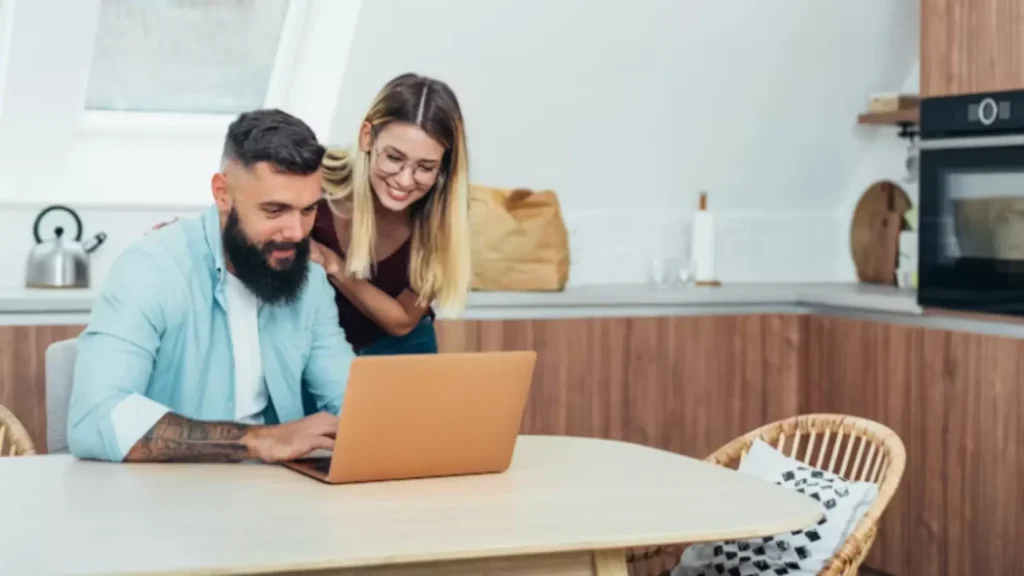 Pareja sentada frente a un portátil revisando una hoja de cálculo de presupuesto nupcial con actitud seria y concentrada, representando la planificación financiera de una boda paso a paso