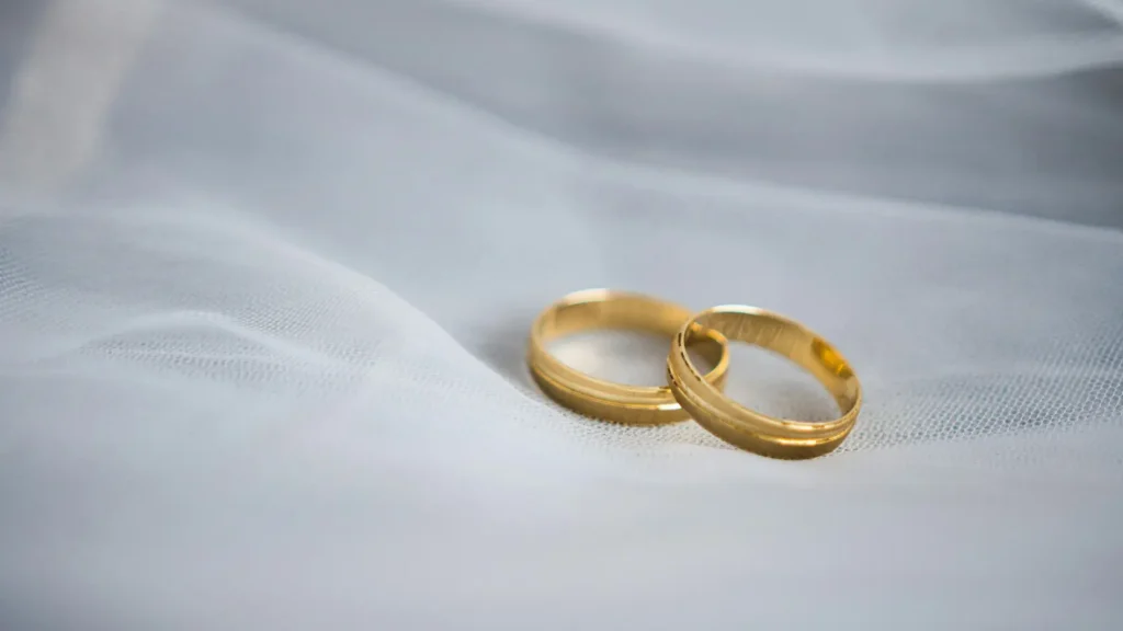 Par de alianzas de boda clásicas de oro sobre superficie de mármol blanco sin elementos decorativos, representando la guía de precio real de alianzas de boda en 2026