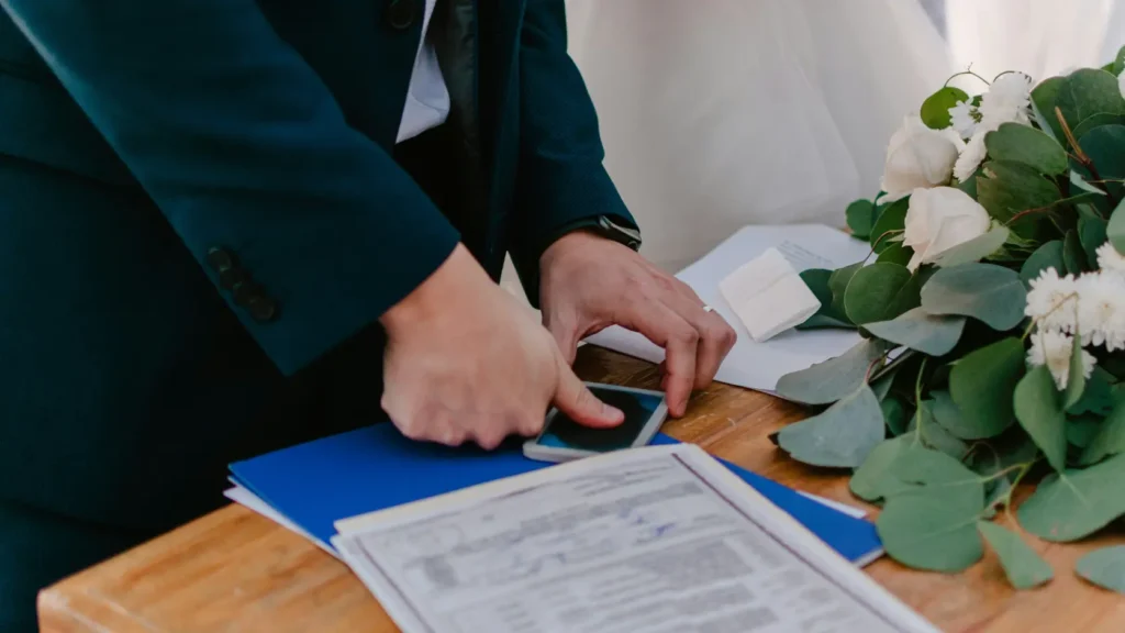 Dossier de boda abierto sobre mesa de madera junto a calculadora y bolígrafo, representando los costes ocultos del presupuesto de boda 2026