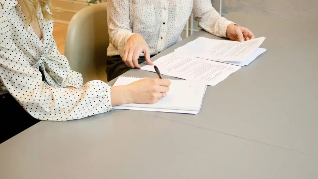 Dos personas trabajando con documentos y carpetas separadas sobre una mesa, representando la independencia patrimonial de la separación de bienes para autónomos y parejas con negocios propios