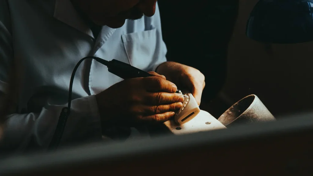 Perito tasador examinando joya con lupa junto a documentos de tasación y certificado gemológico sobre mesa de trabajo, representando el proceso de tasación independiente necesaria para contratar un seguro de joyas con valor convenido para el anillo de compromiso